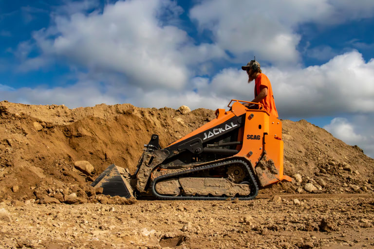 A man using a Scag Jackal to dig up dirt